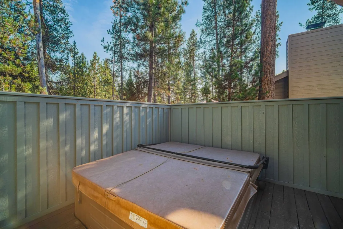 This image captures the enclosed hot tub area set on the wooden deck, surrounded by lush forest. The hot tub is a focal point, offering a perfect spot for relaxation under the canopy of trees. The setting exudes peace and privacy, aligning with the idea of a spa retreat beneath the pines.
