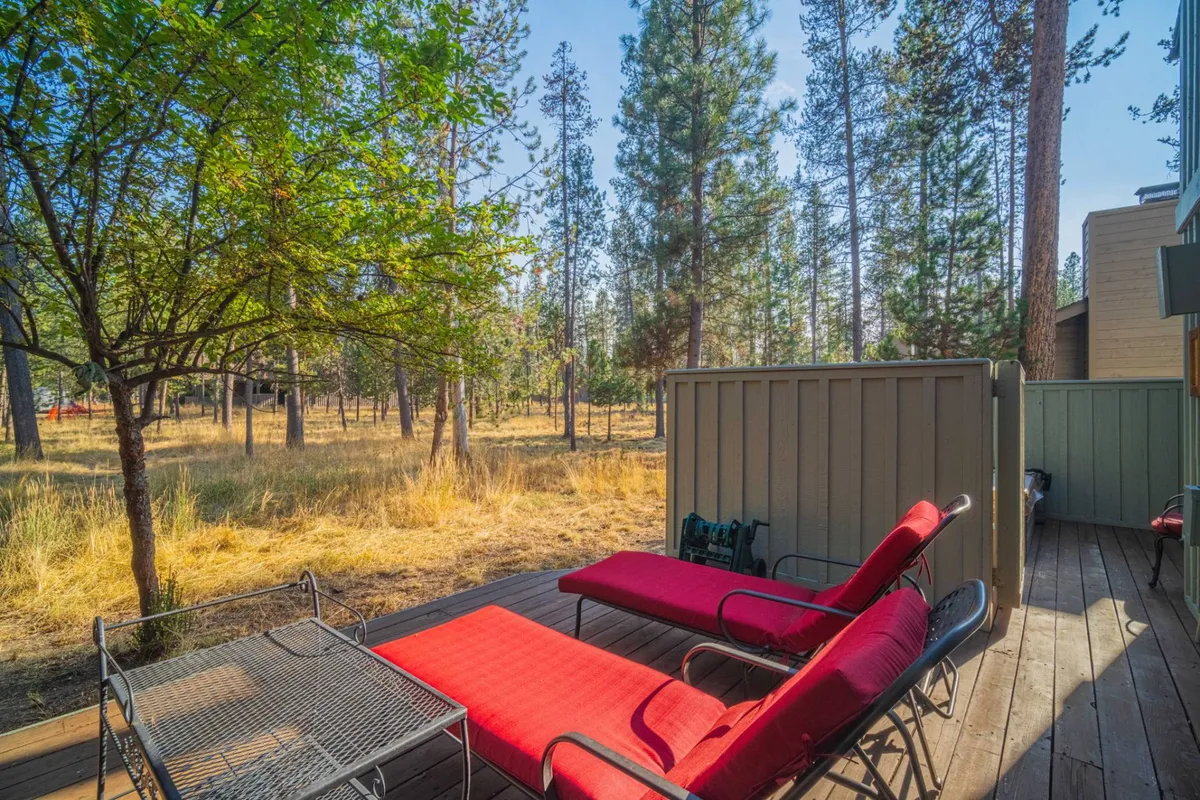 This image displays the deck from a slightly different angle, with red lounge chairs set up for relaxation, surrounded by open space and mature trees. The setting is ideal for reading, socializing, or simply taking in the sunset views, adding another dimension to the outdoor living experience.