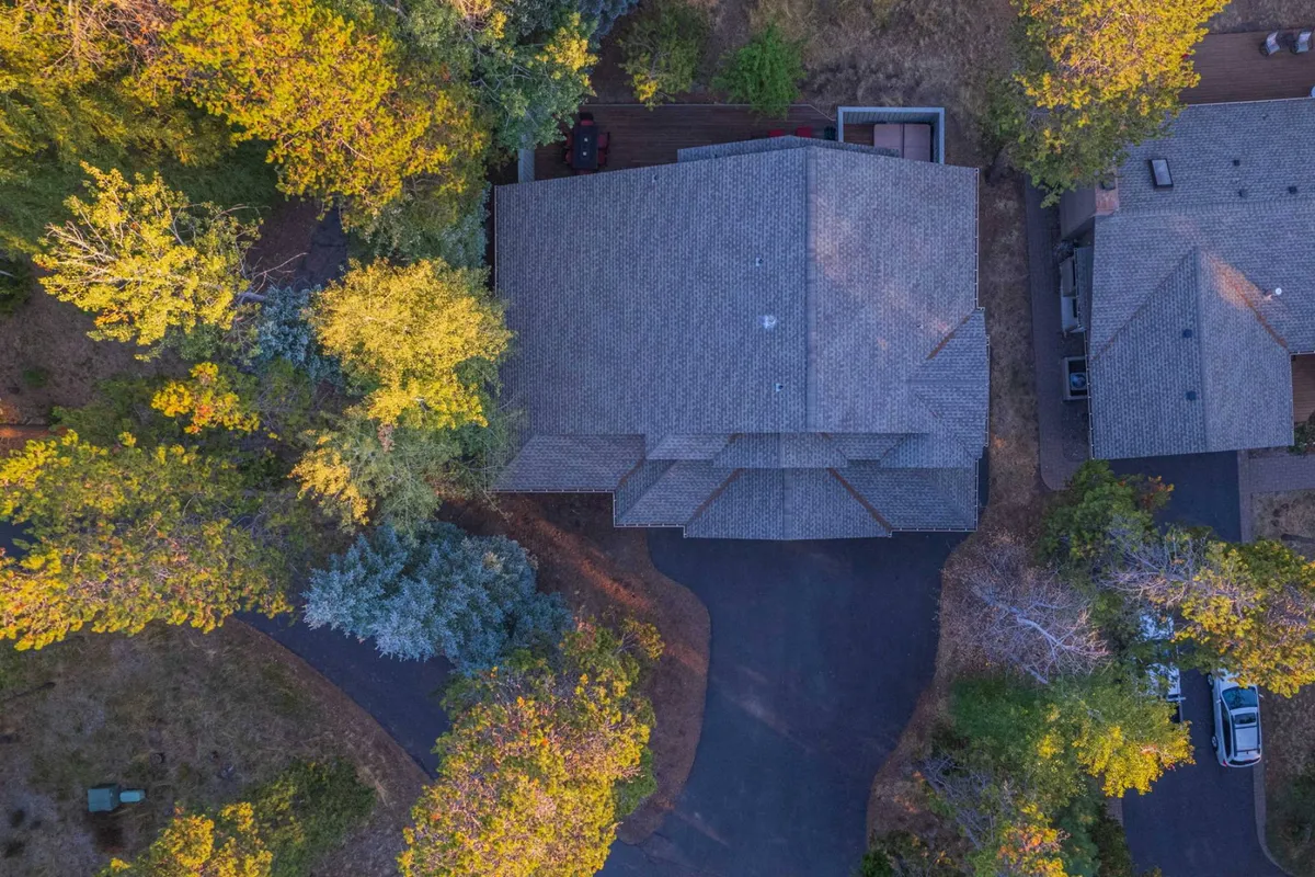 An exterior image showing the house’s roof structure, surrounded by lush trees and a sweeping driveway. The natural environment suggests opportunities for outdoor gatherings, quiet mornings, and enjoying the resort’s amenities.